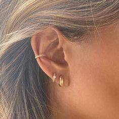 a woman's ear is shown with two small diamond hoops on the side