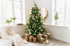 a small christmas tree in the corner of a room with candles and presents on the floor