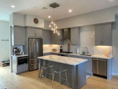 a large kitchen with stainless steel appliances and white counter tops, along with wooden flooring