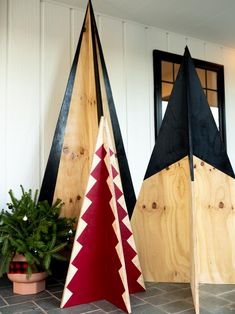 three wooden christmas trees sitting next to each other on a tile floor in front of a white wall