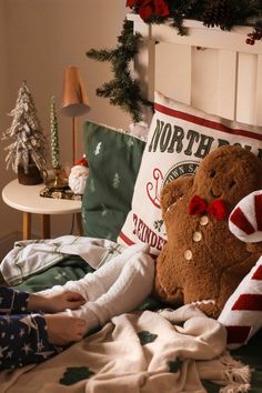 a child laying in bed next to a teddy bear and christmas decorations on the headboard