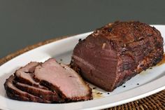 a white plate topped with sliced meat on top of a table