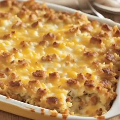 a casserole dish with meat and cheese in it on a wooden table next to utensils