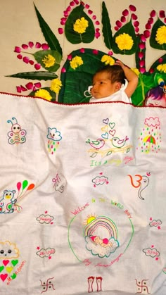 a baby laying on top of a blanket covered in flowers