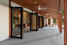 an outdoor covered walkway with sliding glass doors and wood ceilinging on the side of it