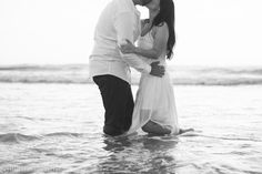 a man and woman kissing in the ocean