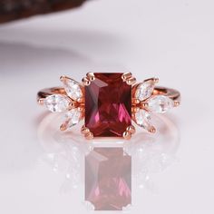 a red diamond ring with three pear shaped diamonds