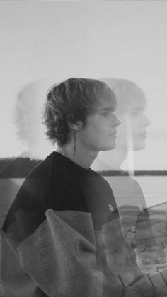 a man sitting in front of a window next to a body of water