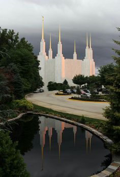 the mormon temple is reflected in a pond on a cloudy day with dark clouds overhead