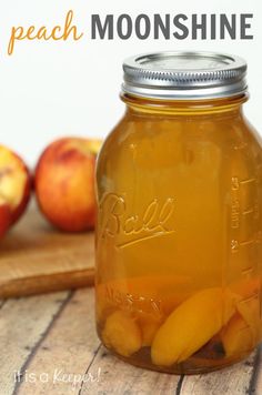 a jar filled with peaches sitting on top of a wooden table next to an apple