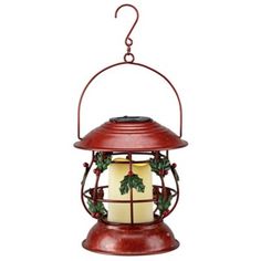 a red lantern with holly decorations hanging from it's side on a white background