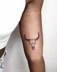 a man's arm with a tattoo on it that has a bull skull in the middle