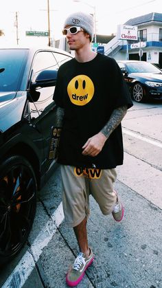 a man walking down the street with a smiley face t - shirt on and pink shoes