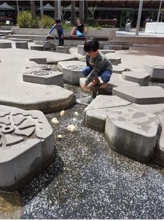 a little boy sitting on top of cement blocks in the middle of an open area