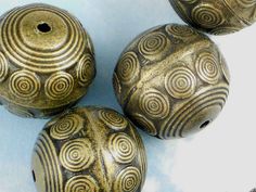 three gold colored beads sitting on top of a white tablecloth with an intricate design