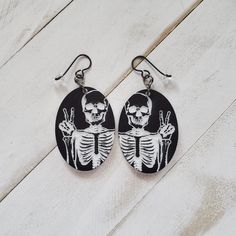 "Fun Skeleton Peace Sign Earrings are cut from acrylic that is black on both sides with a white core.  The earrings measure 1 1/2\" in length, 1 1/8\" in width and 1/8\" in depth. The 20 gauge top shelf Niobium earring wires are 99.9% pure, nickel free and hypoallergenic. This metal is safe for anyone with metal allergies. Earrings are presented in a cloth drawstring bag.  Made with aloha in Hawaii, USA." Black Skull Earrings For Gift, Novelty Black Skull Earrings, Spooky Black Drop Earrings, Nickel Free Black Skull Earrings, Nickel-free Black Spooky Earrings, Handmade Black Skull Earrings, Cat Clock, Goth Earrings, Halloween Jewelry