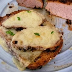 two slices of meatloaf on a plate with melted cheese and chives in the middle