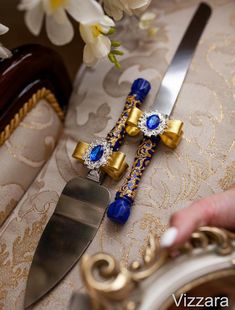 a pair of blue and gold jeweled scissors on a table with flowers in the background