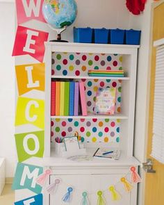 a colorful welcome sign hanging from the side of a white bookcase