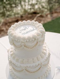 a three tiered white cake sitting on top of a table