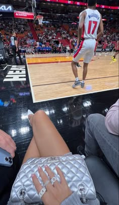 a woman sitting on top of a basketball court next to a man holding a cell phone