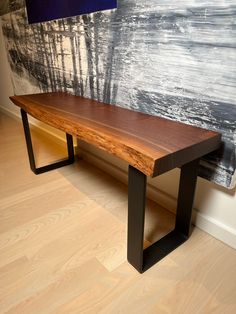 a wooden bench sitting in front of a painting on the wall next to a hardwood floor