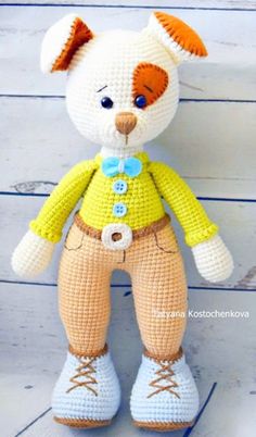 a crocheted teddy bear wearing a yellow shirt and brown pants with blue shoes