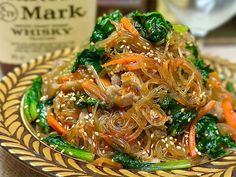 a plate full of stir fry with vegetables and sesame seeds on the side, next to a bottle of wine