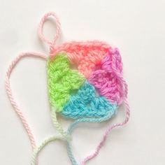 the crocheted hat is multicolored and sits on a white surface next to a pair of scissors