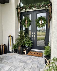 the front door is decorated for christmas with evergreen wreaths