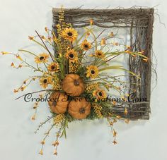 an arrangement of sunflowers and pumpkins in a frame