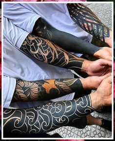 two men with tattoos on their arms sitting next to each other