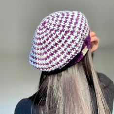 a woman with grey hair wearing a purple and white hat on her head, back to the camera