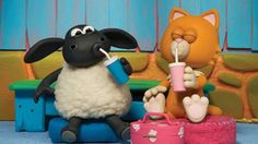 a toy sheep sitting on top of a bench next to a stuffed animal and drink from a cup