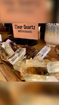 many crystals are on a table with a sign that says clear quartz with inclusions