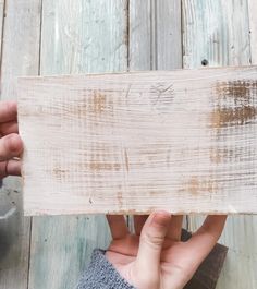 two hands holding up a piece of wood that has been stained white and is being held by another person