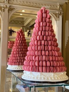 pink macaroons stacked on top of each other in front of a glass case