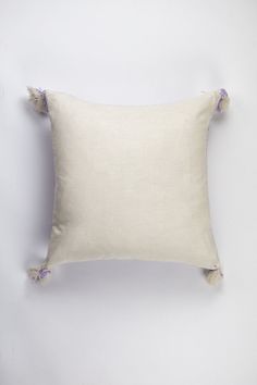 a white pillow with tassels on the sides and a pink flower in the middle