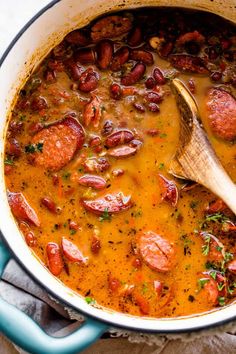 sausage and bean soup in a blue pot with a wooden spoon on the side, ready to be eaten