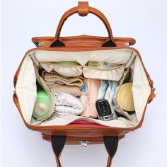 an open suitcase filled with items on top of a white table next to a wall