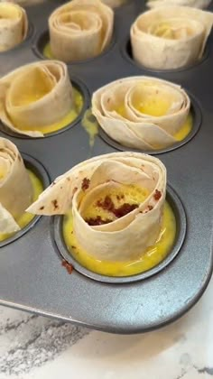 a muffin tin filled with cupcakes covered in frosted pastry wrappers