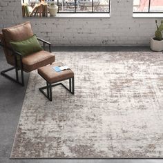 a chair and ottoman in an empty room with brick walls, windows and potted plants