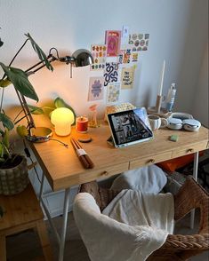 a wooden desk topped with a laptop computer next to a lamp and potted plant