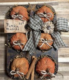 four pumpkins in a box with a sign on the front and two cinnamon sticks next to them