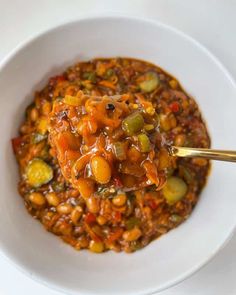 a white bowl filled with beans and carrots on top of a table next to a spoon