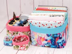 several different types of fabric and sewing supplies are sitting on a white wooden surface,