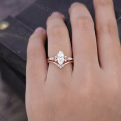 a woman's hand with a diamond ring on top of her finger and an open box in the background