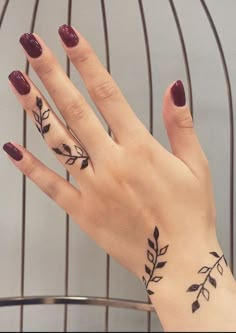 a woman's hand with two tattoos on it and one has a leaf design