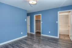 an empty room with blue walls and wood floors