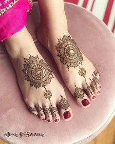 a woman's feet with henna tattoos on their legs and toes, sitting on a pink chair